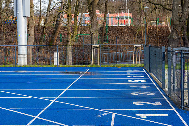 Beautiful athletic mid-adult woman stretching before running on a running track outdoors.