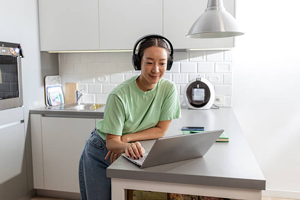 istock Woman with headphone in the kitchen, using a laptop 2208282455