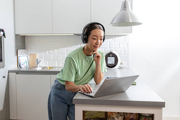 istock Woman with headphone in the kitchen, using a laptop 2208282464