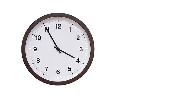 istock A simple round wall clock with a dark brown frame and a white face displaying 15.55/03.55. Isolated on a white background, perfect for time-related concepts, deadlines, and schedule themes. 2208283059