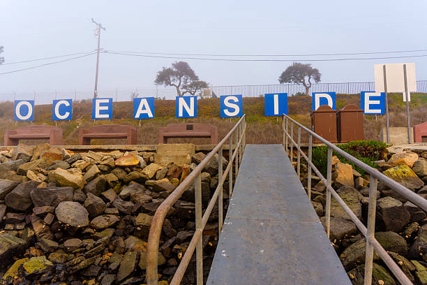 Oceanside, California - January 3, 2025: Clear view of the Oceanside sign with rocky foreground and coastal pathway, taken during a foggy morning in Oceanside, California.