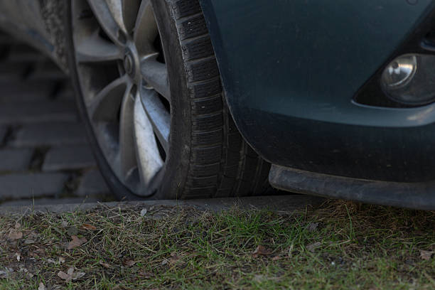 istock Car Tire is Over Curb Positioned on Grass Vehicle Parking Scenario 2208287427