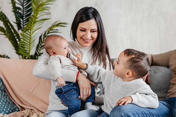 Young mother playing with her baby and toddler in apartment.