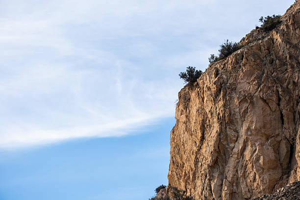 Majestic rocky cliffs against a clear blue sky with sparse vegetation.