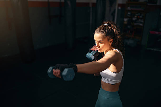 istock Female kickboxer shadowboxing with dumbbells 2208288818