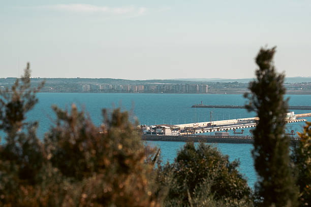 Scenic coastal landscape with distant buildings and harbor pier.