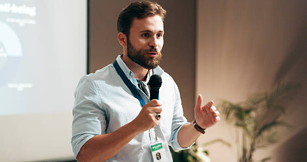 istock Businessman, development and presentation with speaker in conference room for wellness training. Education, forum speech and microphone with corporate coach on stage for public relations or seminar 2208292062