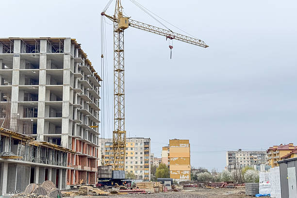 istock A tall construction crane stands beside a partially built concrete structure on a construction site 2208292418
