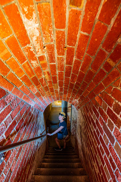 Woman walking down stairs into old brick tunnel, Fort Nepean, Mornington Peninsula, Victoria, Australia