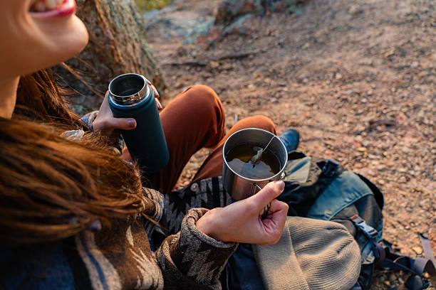Smiling hiker savoring a hot cup of tea during a relaxing break on a bright, sunny day in the heart of nature's beauty