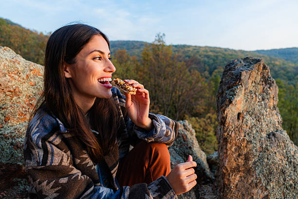 Young hiker eating energy bar enjoying mountain landscape