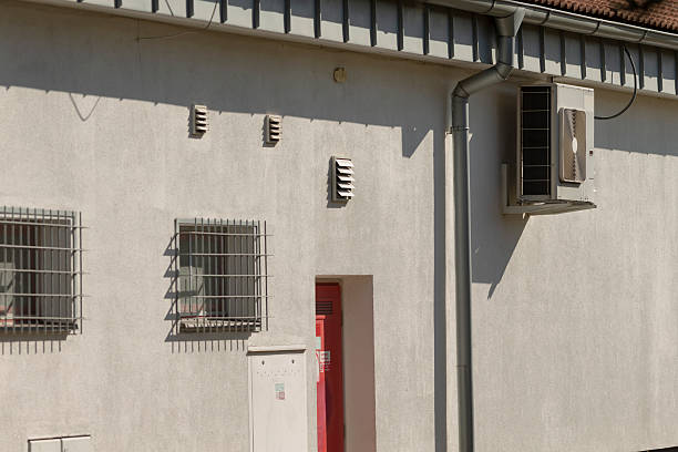 A white building featuring a bright red door alongside a window that has metal bars installed on it for security purposes
