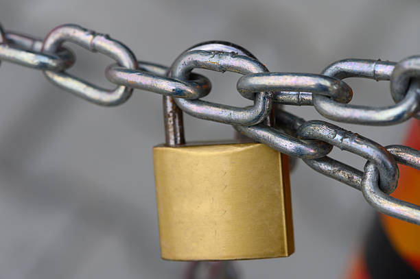 istock Metallic chain secured with a shiny golden padlock, symbolizing strength and safety in a bustling urban environment 2208303034