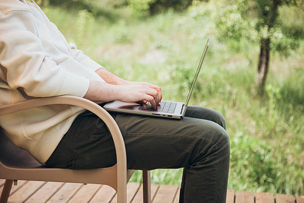 istock Man works on laptop while sitting relaxed on chair, traveling with tent. 2208303833