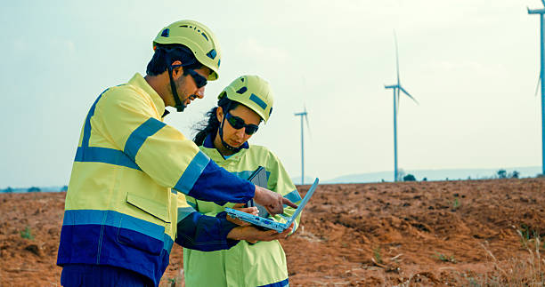 istock Renewable energy engineers are intently reviewing data on a laptop, contemplating the expansive turbine field before them. Green ecological power generation wind sustainable energy. 2208308030