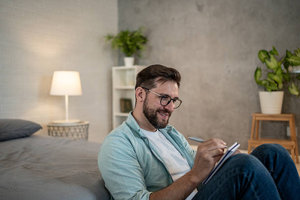 istock Smiling man writing on notepad in bedroom 2208311952