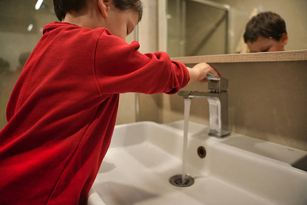 istock Child Turning Off Bathroom Faucet 2208312200