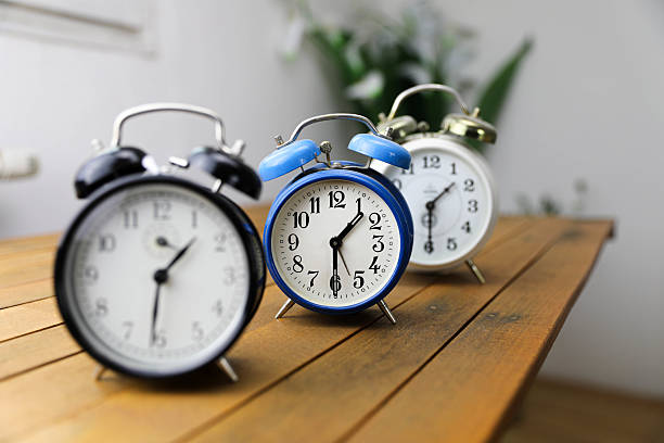 istock Vintage Alarm Clocks on a Wooden Board 2208313876