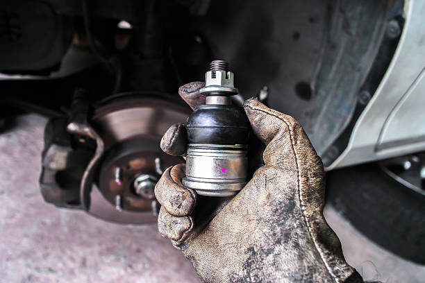 Mechanic holding new ball joint for vehicle suspension repair