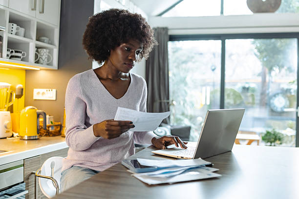 istock Woman managing finances while working from kitchen with documents and laptop 2208325916