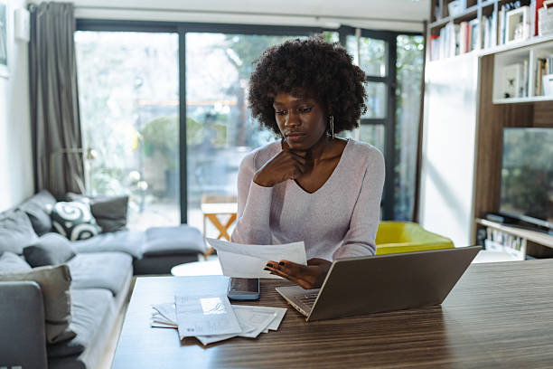 istock Young woman managing finances at home with laptop and documents 2208326849
