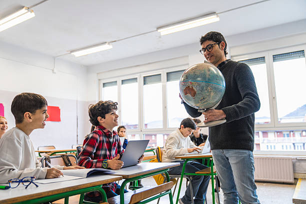 istock Teacher showing globe to elementary age students during geography lesson 2208330386