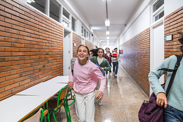 istock Cheerful students running in school hallway after class 2208334130