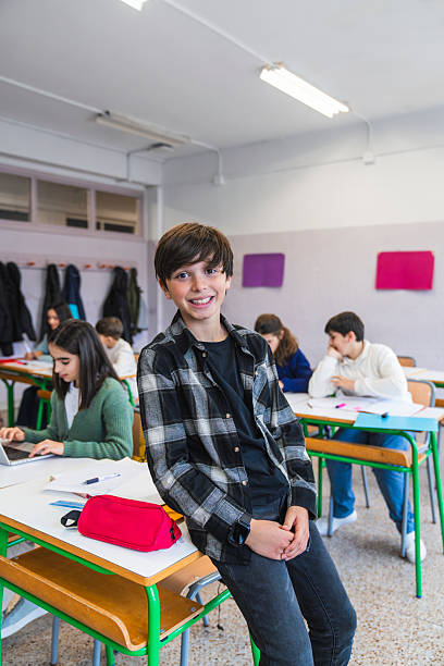 istock Portrait of smiling student leaning on desk in classroom 2208335172