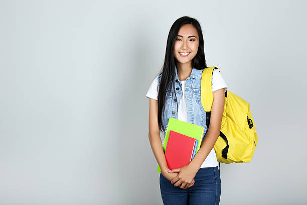 istock Young woman with books, notepads and backpack on grey background 2208338054