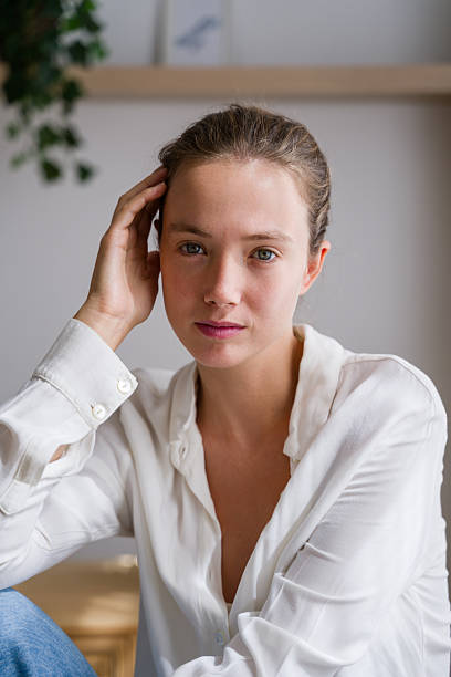 Portrait of a beautiful young woman with blue eyes touching her hair and looking at camera