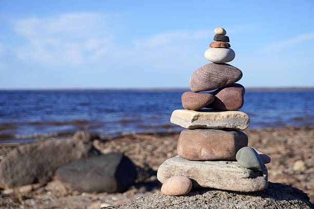 Colorful pebbles stacked and balanced on a rock by the sea create a serene and meditative scene
