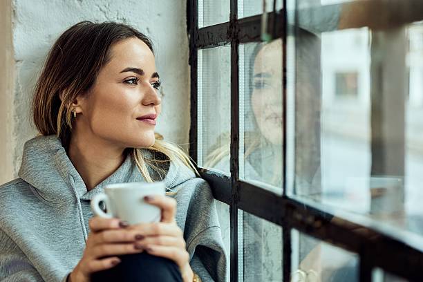 istock Woman Enjoys Coffee While Relaxing by the Window with Inspiring Reflections 2208343937