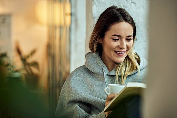 istock Woman Smiling While Reading a Book and Relaxing With a Cup of Coffee 2208343943