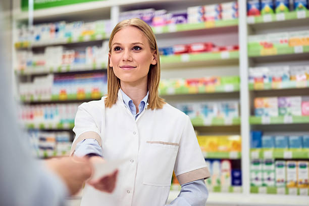 istock Smiling Pharmacist Assisting Customer in Bright Pharmacy Stocked With Medicines 2208345492