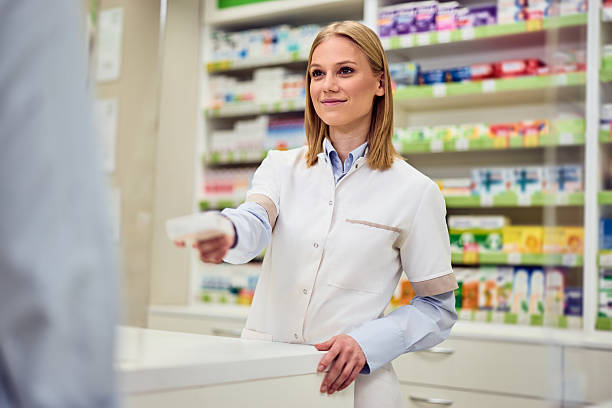 Professional Pharmacist Assisting Customer in Modern Well-Organized Pharmacy Store