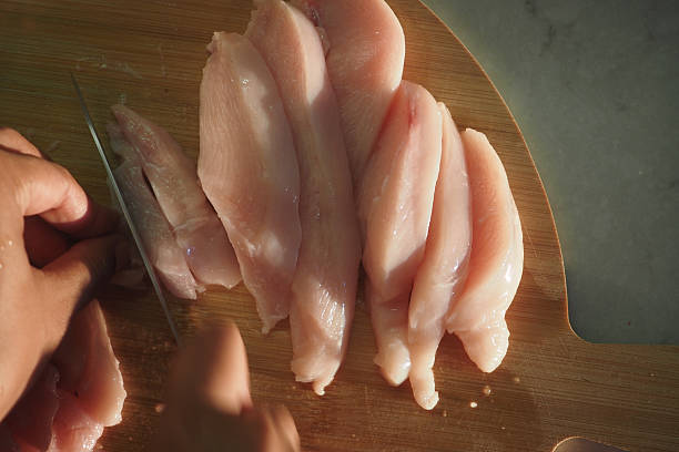 istock Fresh Chicken Breast Is Being Skillfully Sliced on a Wooden Cutting Board 2208345571