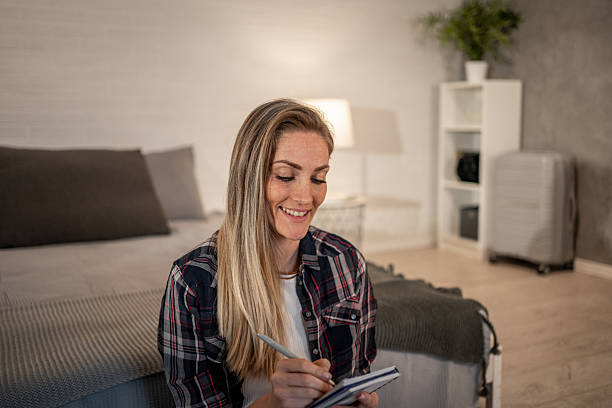 istock Smiling woman writing on notepad in hotel room 2208346246