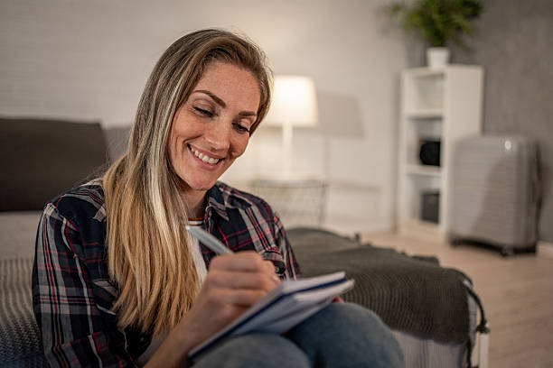istock Smiling woman writing on notepad at home preparing for trip 2208346287