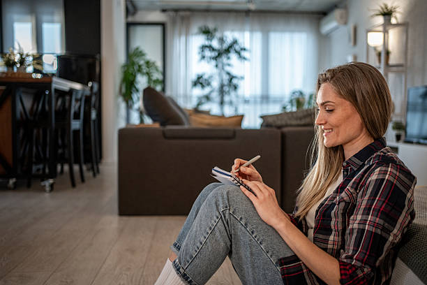 istock Young woman taking notes while relaxing on floor at home 2208346299