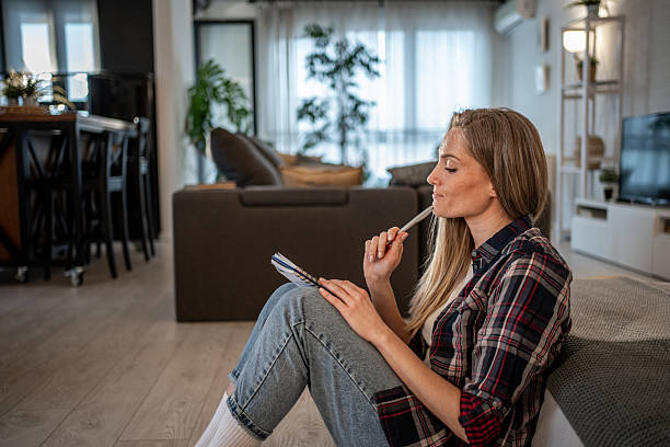 istock Young woman taking notes and thinking in her living room 2208346308