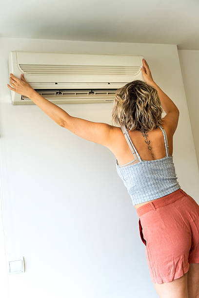 istock Woman installing air conditioning unit on wall at home 2208347250
