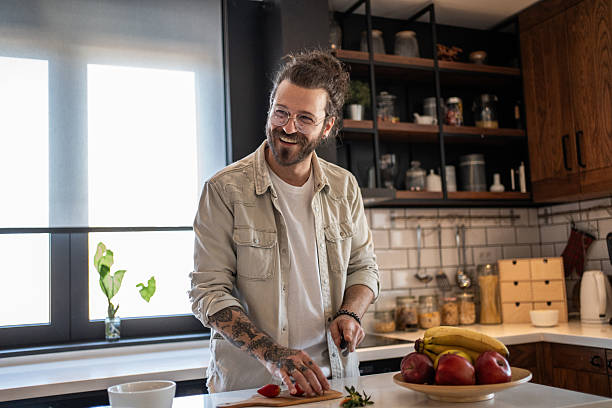 istock Happy man cutting strawberries in a modern kitchen 2208349132