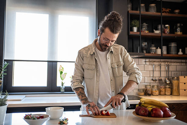 istock Young man cutting strawberries in a modern kitchen 2208349150