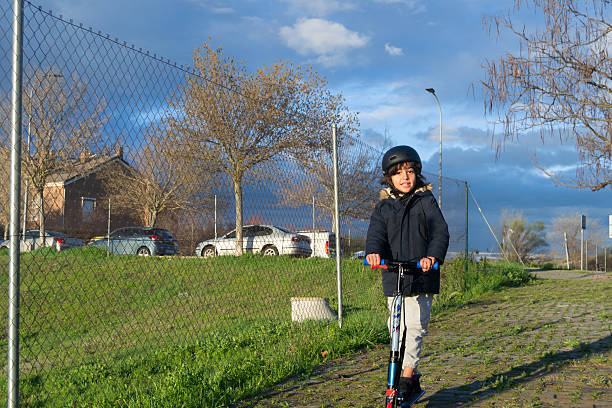 boy riding a scooter on the sidewalk in the urbanization