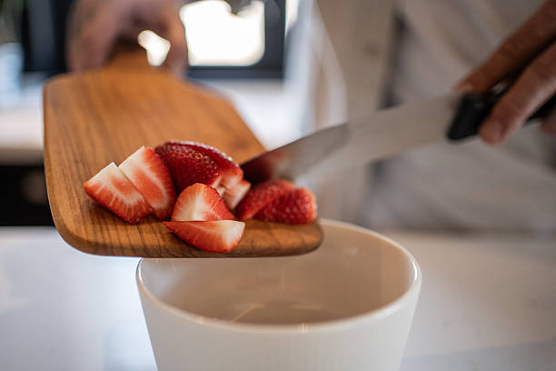 istock Chef sliding chopped strawberries from cutting board into bowl 2208349218