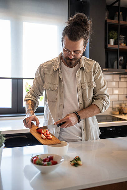 istock Young man cutting strawberries in a modern kitchen 2208349220