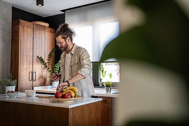 istock Young man preparing a healthy snack with fresh fruit in his modern kitchen 2208349304