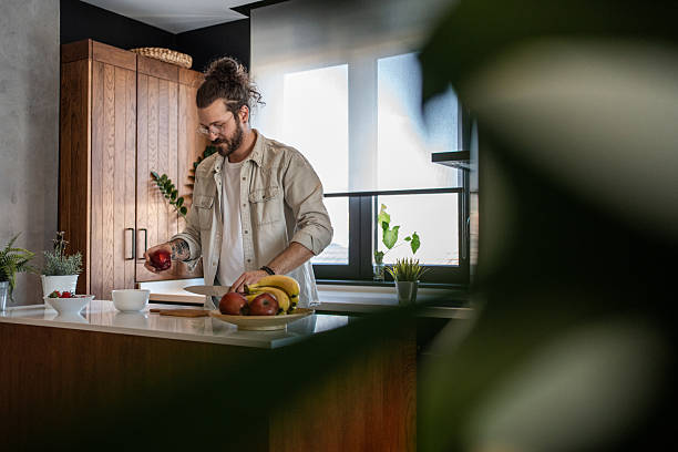 istock Young man preparing a healthy fruit salad in his modern kitchen 2208349352