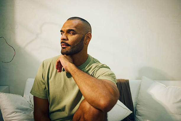 istock Young aboriginal australian man sitting thoughtfully on sofa in morning light 2208354270
