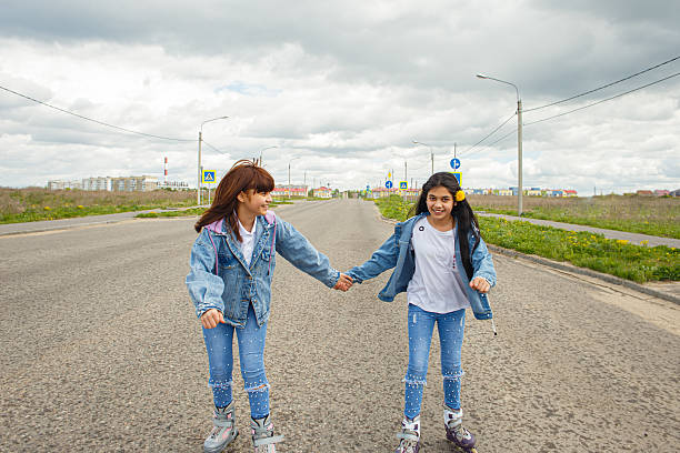 Two cute smiling teenage girls are roller-skating. A healthy lifestyle.
